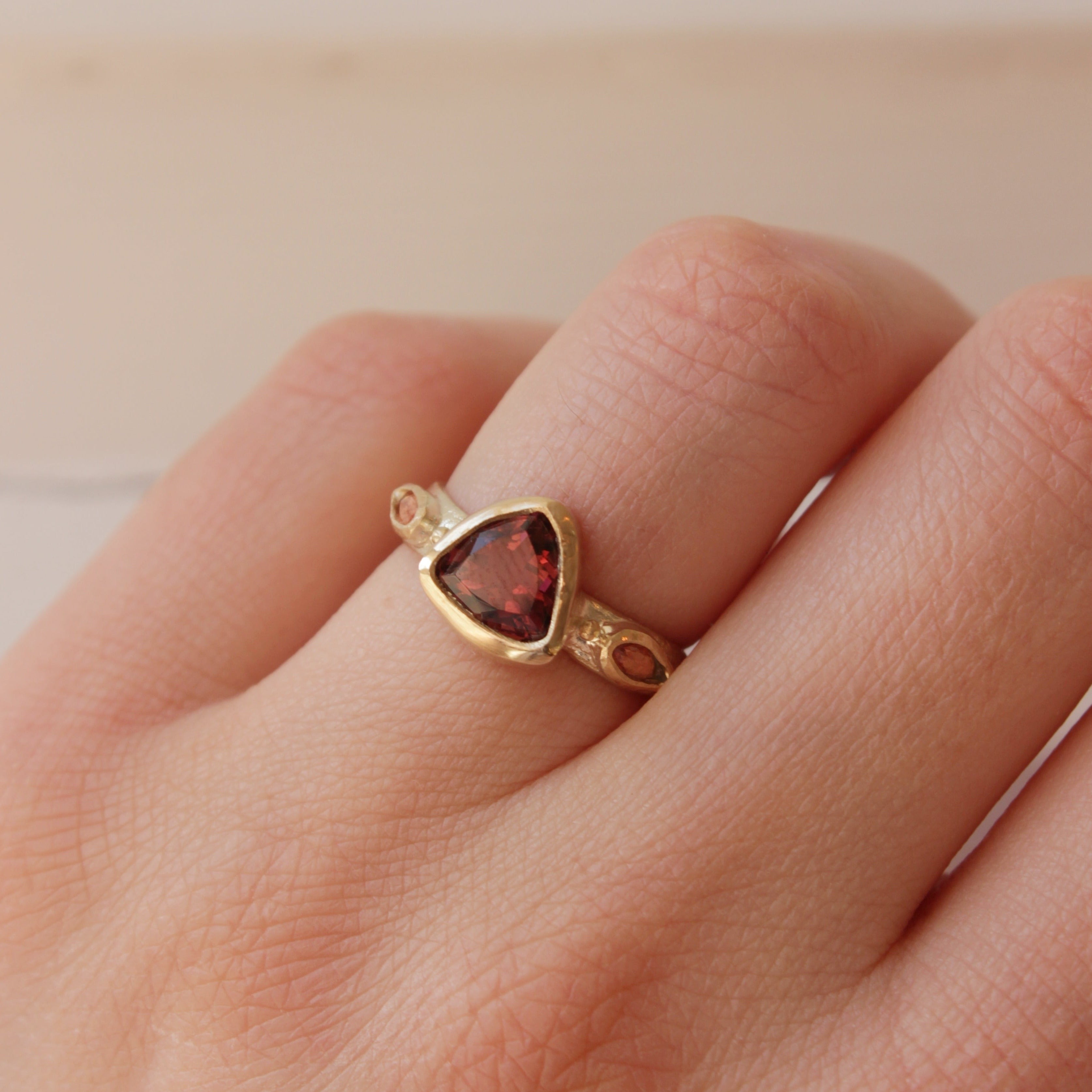Alternative pink tourmaline engagement ring, handcrafted by Josie Mitchell jewellery in Frome, Somerset. Featuring a stunning deep pink tourmaline stone with peach coloured sapphires on either side and delicate gold granules.