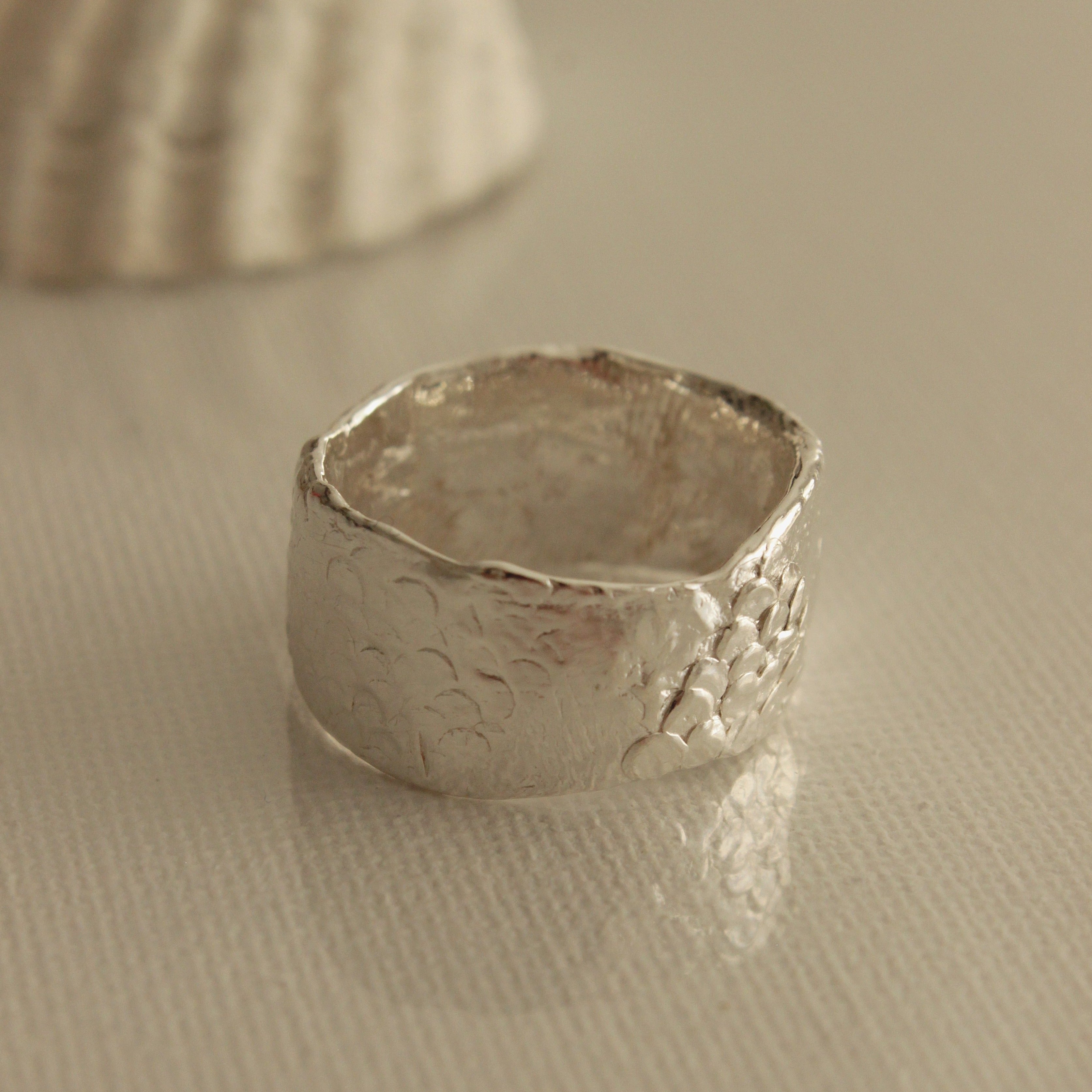 The Ancient Poet ring appears as though it has been plucked from the depths of the ocean. Scattered scales and hidden finger prints caress this organically formed band and offer a unique magic to this timeless piece. Enjoy this treasure everyday, along with the calming and tranquil effects it brings.
